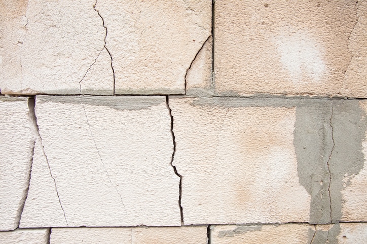 Cracks on the white wall blocks. The destruction of the wall. Background texture